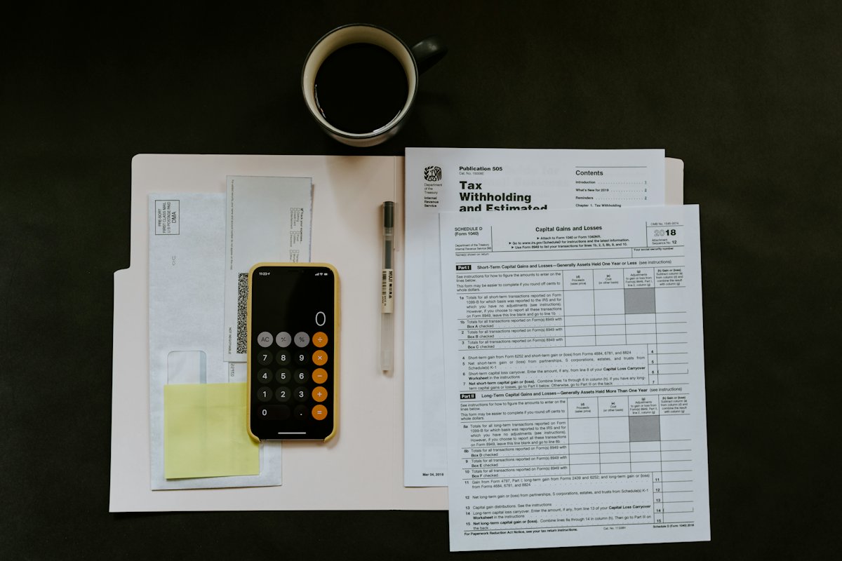Tax forms, a calculator and a pen on a desk
